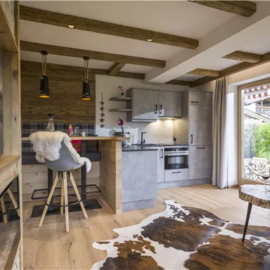 A modern kitchen with wood paneling and stylish furniture. The room features large windows that let in plenty of light.