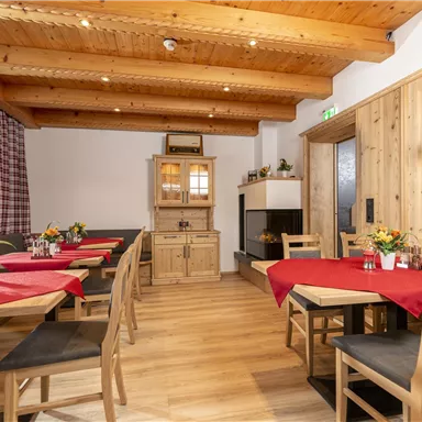 Ein gemütliches Restaurant mit Holzdetails und roten Tischdecken. Die Atmosphäre ist einladend und warm.