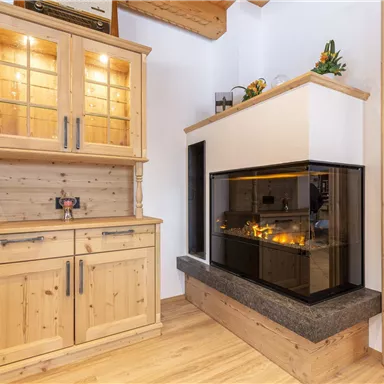 Ein moderner Wohnraum mit einem eleganten Kamin und einem Holzregal. Die warmen Holzfarben schaffen eine gemütliche Atmosphäre.