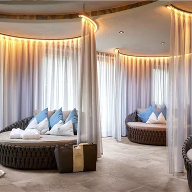 A stylish spa with cozy lounge areas and soft lighting. The seating furniture is equipped with cushions in blue and white and radiates relaxation.