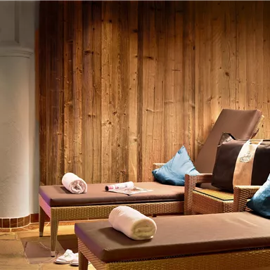 A tranquil spa area with comfortable loungers and a warm wood look. Soft lighting creates a relaxing atmosphere.