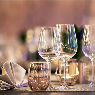 An elegant table with glasses and a folded napkin. Soft light creates a festive atmosphere.