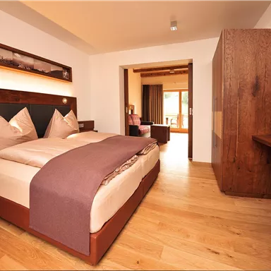 Ein modernes Schlafzimmer mit einem großen Bett und Holzdetails. Die warme Farbpalette sorgt für eine gemütliche Atmosphäre.