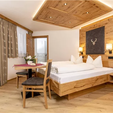 Ein gemütliches Hotelzimmer mit Holzdekor und einem großen Fenster. Das Zimmer verfügt über ein Doppelbett, einen Tisch und Stühle.