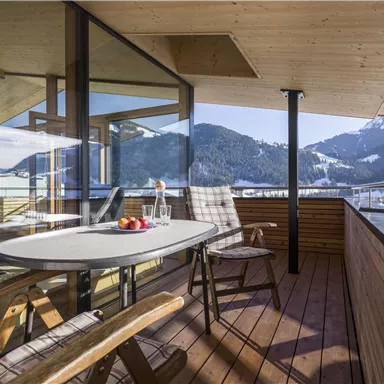 A beautiful balcony with a view of the mountains. On the table are drinks and fresh fruit.