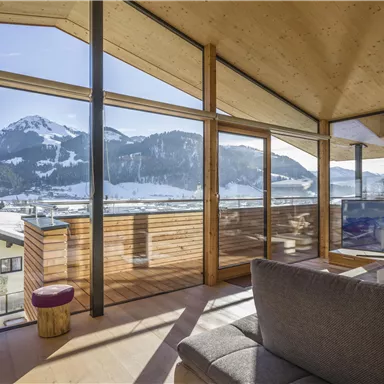 A modern apartment with large windows and a view of snow-covered mountains. The brightly designed space invites relaxation.