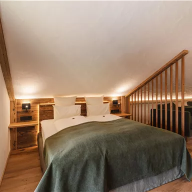 Ein gemütliches Schlafzimmer mit einem Doppelbett und Holzverkleidung. Die sanfte Beleuchtung schafft eine entspannte Atmosphäre.