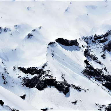 A snow-covered mountain with majestic peaks and a cloud-covered sky. The landscape exudes tranquility and untouched beauty.