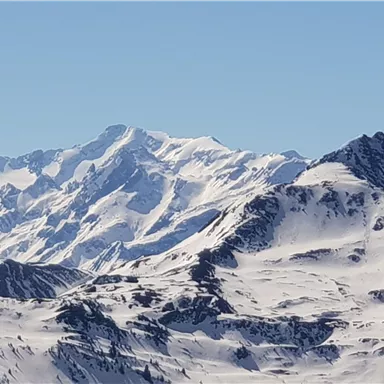 Snow-covered mountains under a clear blue sky. The impressive peaks display a breathtaking winter landscape.