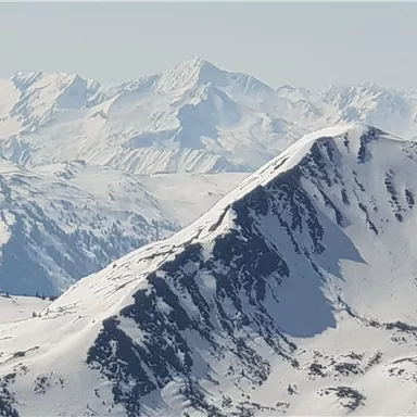A breathtaking mountain landscape with snow-capped peaks. The sky is clear and the light reflects off the white rocks.