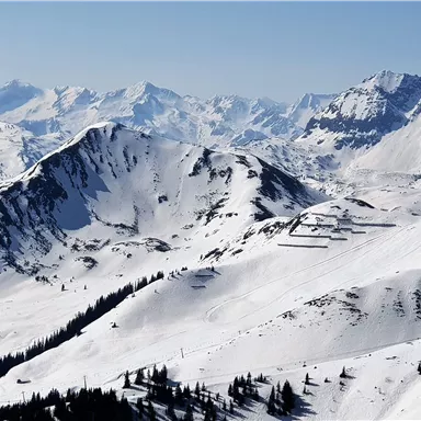A picturesque winter landscape with snow-covered mountains. The clear sky offers a breathtaking view of the surrounding peaks.