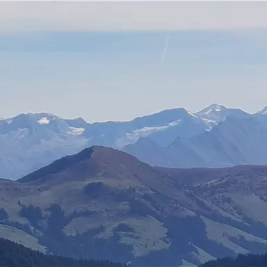 An impressive mountain landscape with snow-capped peaks and gentle slopes. The sky is clear and blue, highlighting the beauty of nature.