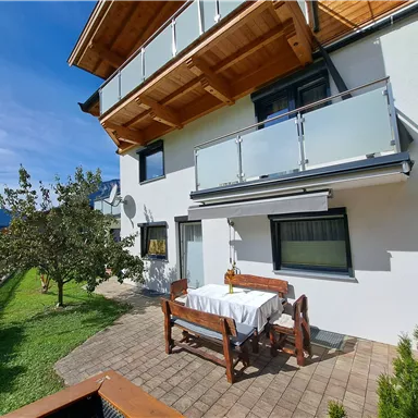 A modern house with a balcony and an outdoor terrace. The garden is green and inviting, perfect for relaxing moments outside.