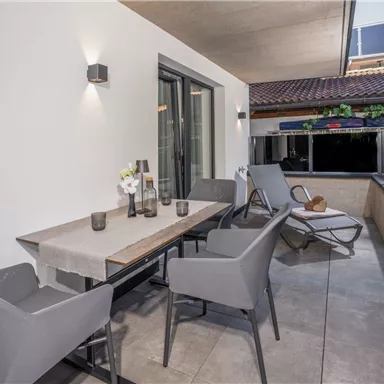 A modern terrace with a table and chairs. The surroundings are bright and inviting, perfect for relaxing hours outdoors.