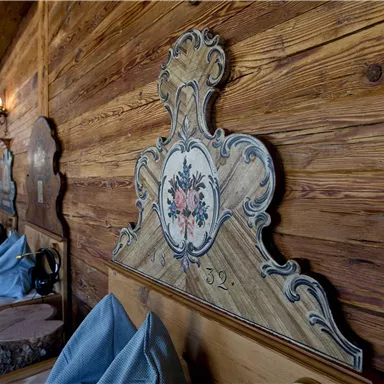 Ein gemütlicher Raum mit Holzverkleidung und dekorativen Bettköpfen. Die Einrichtung strahlt eine warme und einladende Atmosphäre aus.