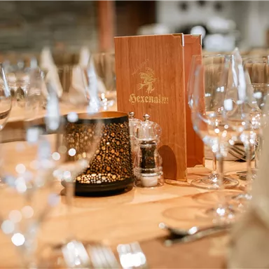 Ein elegant gedeckter Tisch mit Glaswaren, Besteck und einer Menükarte. Die Atmosphäre ist stilvoll und einladend.