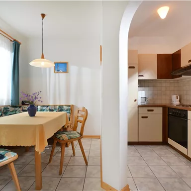 A bright kitchen with a dining table and chairs. The furniture is modern and the walls are painted in light colors.