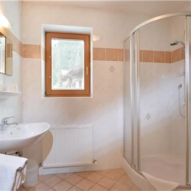 A bright bathroom with a shower and sink. The window provides natural light.