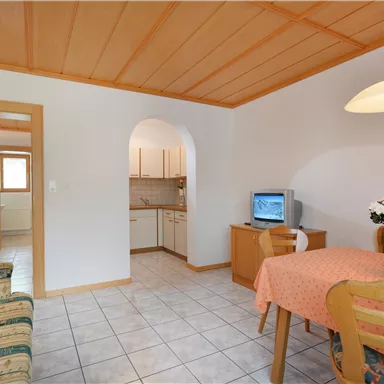 A cozy living area with a table, chairs, and a couch. The kitchen is open and invites cooking.