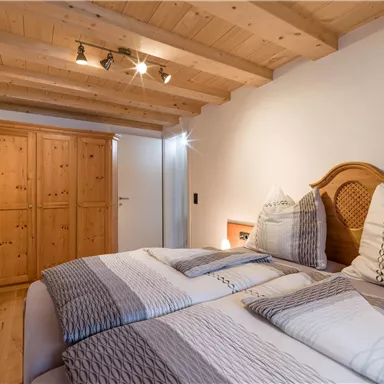 Ein gemütliches Schlafzimmer mit zwei Betten und einer Holzdecke. Der Raum hat einen Kleiderschrank und sanfte Beleuchtung.