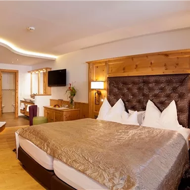 A cozy bedroom with a large double bed and elegant wooden furniture. The atmosphere is warm and inviting, perfect for relaxing.