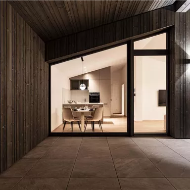 A modern living room featuring a dining table and elegant chairs is visible through large windows. The walls are made of wood, creating a cozy atmosphere.