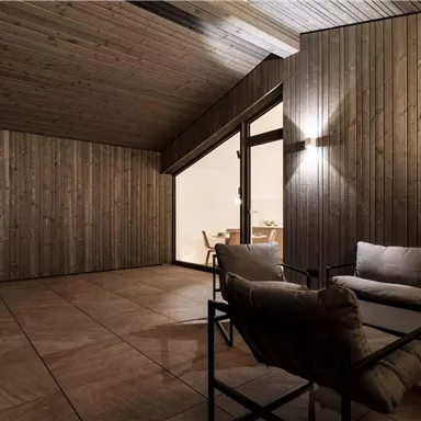 A modern interior with wooden walls and a cozy seating area. The light creates a warm, inviting atmosphere.