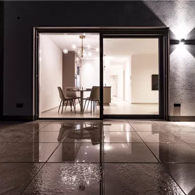 A modern interior view with a glass front and a bright, inviting room. The floor reflects the light and the furniture is carefully arranged.