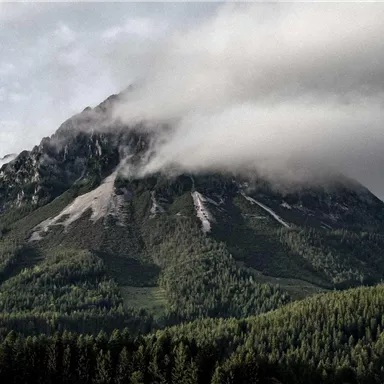 A majestic mountain, surrounded by dense forests and misty clouds. The landscape exudes tranquility and beauty.