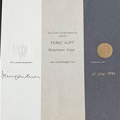 Ein Zertifikat mit dem Titel "Umweltsiegel Tirol". Es zeigt den Namen eines Hauses und das Datum der Ausstellung.