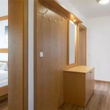 Ein heller und moderner Raum mit Holzdekor. Im Hintergrund sind ein Doppelbett und ein Schrank zu sehen.