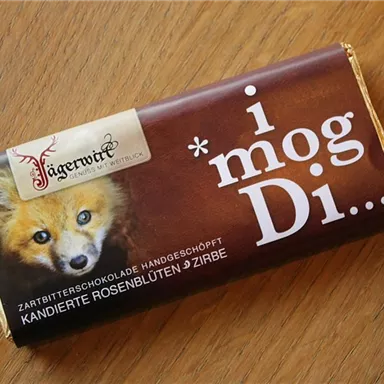 Eine Schokoladentafel mit der Aufschrift „i mog Di...“ und einem Bild eines Fuchses. Die Verpackung zeigt eine elegante Gestaltung in Braun- und Goldtönen.