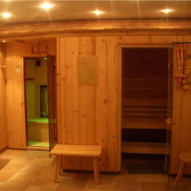 Ein gemütlicher Wellnessbereich mit Holzverkleidung. Die Sauna ist abgedunkelt und bietet einen entspannenden Raum zur Erholung.