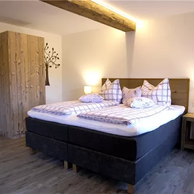A cozy bedroom with two beds and wooden details. The soft lighting creates a relaxed atmosphere.
