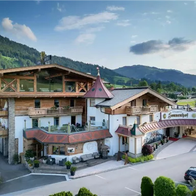 Ein charmantes Hotel im alpinen Stil umgeben von grünen Bergen. Die Fassade kombiniert Holz und traditionelle Elemente.