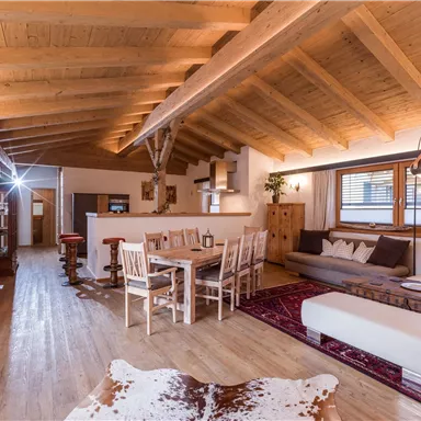 Ein modernes Wohn- und Esszimmer mit Holzbalkendecke. Der Raum ist hell und gemütlich eingerichtet, ideal für Entspannung und gesellige Abende.