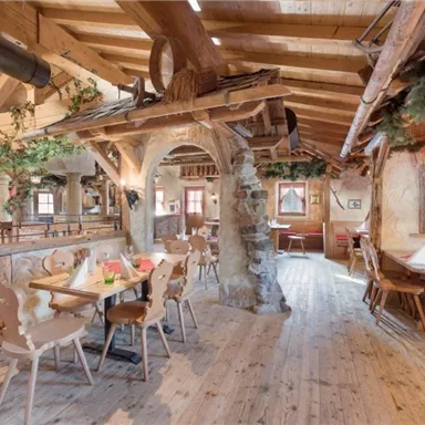 Ein gemütliches Restaurant mit Holzdekor und einem rustikalen Ambiente. Die Tische sind liebevoll gedeckt und es gibt einen Kamin in der Ecke.