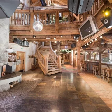 Ein gemütlicher Innenraum mit rustikalem Holzdesign und einer Wendeltreppe. Die Bar ist gut eingerichtet und der Boden besteht aus Fliesen und Stein.