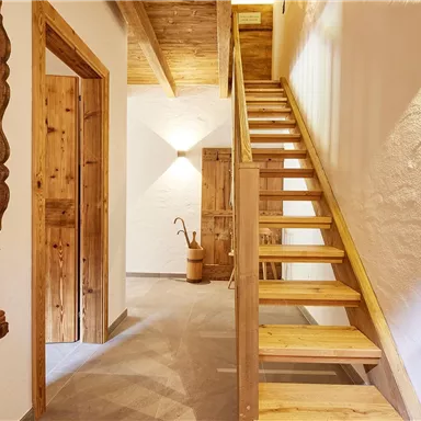 Ein einladender Flur mit Holztreppe und warmen Holzelementen. Der Raum ist hell und freundlich gestaltet.