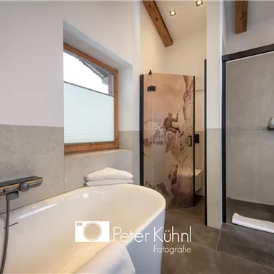 Ein modernes Badezimmer mit einer freistehenden Badewanne und einem Glaskabine für die Dusche. Helle Wände und Holzdetails sorgen für eine freundliche Atmosphäre.