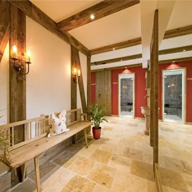 An elegant entrance area with wooden paneling and warm lighting. In the center stands a wooden bench and some plants create an inviting atmosphere.