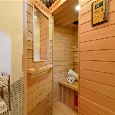 Eine gemütliche Sauna aus Holz mit Handtüchern und sanfter Beleuchtung. Der Raum bietet eine entspannende Atmosphäre zum Relaxen.