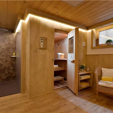 Ein stilvolles Badezimmer mit Holzwänden und warmem Licht. Es gibt eine Dusche auf der linken Seite und einen gemütlichen Sitzbereich mit Pflanzen.