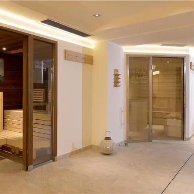 A modern wellness area with several saunas and wooden interiors. The room is brightly and invitingly designed, ideal for relaxing.