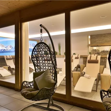 An elegant relaxation area with two rocking chairs and a view of modern loungers. The large window front lets in plenty of light and offers a beautiful view of the mountains.