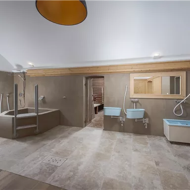 A modern bathroom with elegant tiles and a bright, minimalist design. It features a bathtub and two sinks.