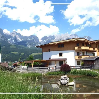 Ein malerisches Dorf mit traditionellen Gebäuden und einer majestätischen Berglandschaft im Hintergrund. Der Himmel ist klar und blau, ideal für eine Ferienatmosphäre.