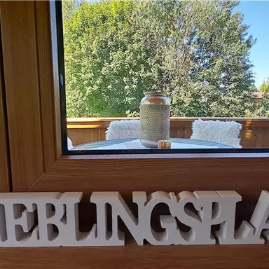 A window view of a green landscape with trees and mountains. In front of the window stands the word "FAVORITE PLACE".