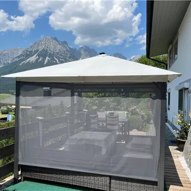 Ein gemütlicher Pavillon mit Blick auf die Berge. Im Inneren sind Tische und Stühle auf einer Terrasse.