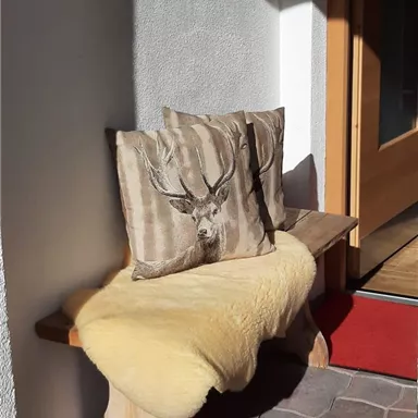 A cozy bench with a yellow fur and two cushions featuring a deer antler motif. The area is well-lit and feels welcoming.